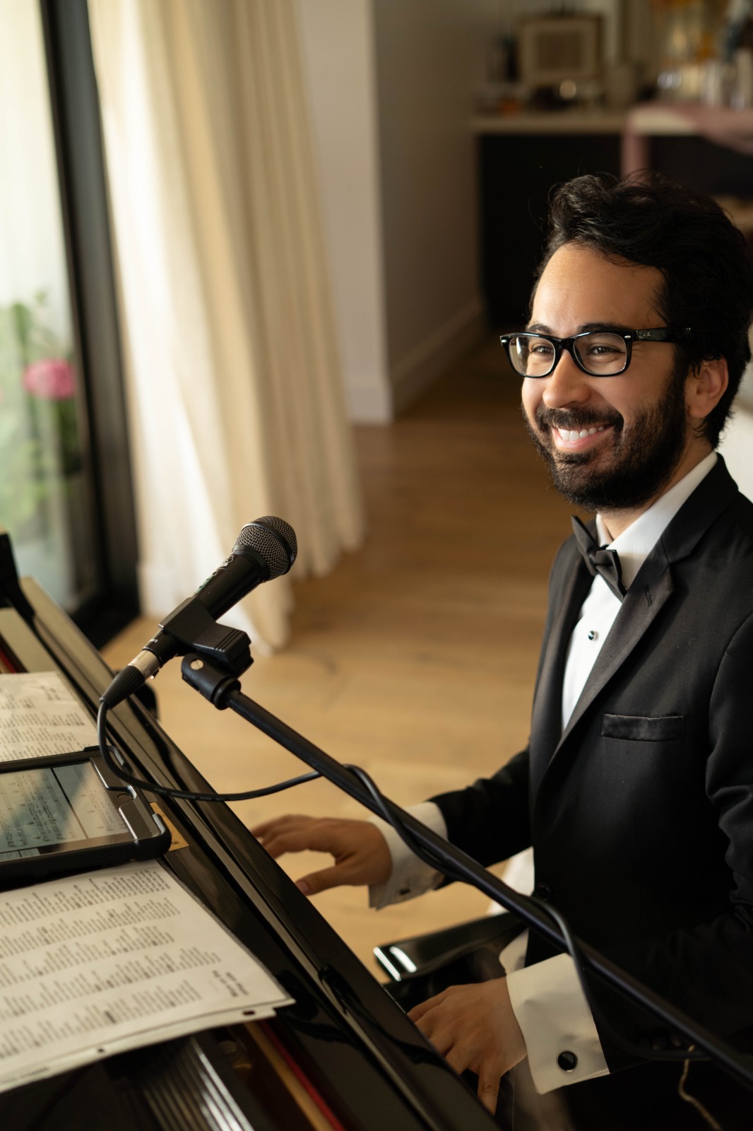 Steven in black tie singing at the piano with a microphone